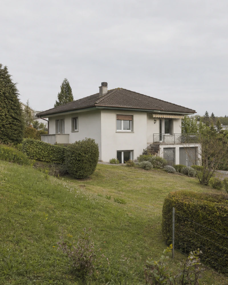 Bestehendes Wohnhaus auf einem geneigten Grundstück mit Garten und umgebender Wohnbebauung.